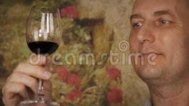 面人在品尝前看着酒杯里的红酒。 喝红酒的男人